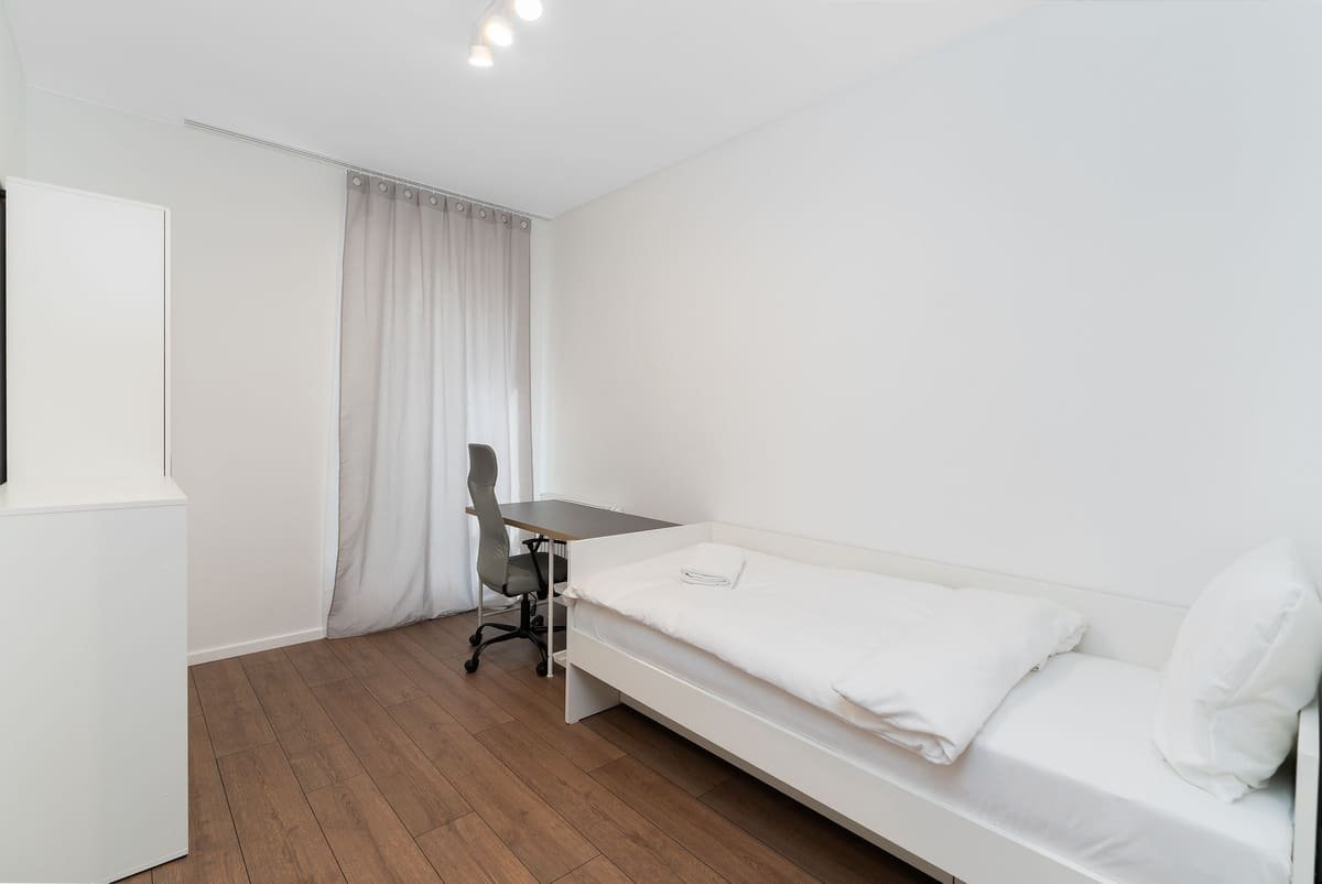 Aufgeräumtes Einzelzimmer mit Bett, Schreibtisch und Schrank